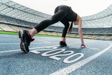 Genç sporcu kadın 2020 harf yakınlarındaki koşu pistinde poz vermeye başladı.