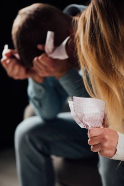 selective focus of unhappy woman holding crumpled lottery ticket near upset man clipart