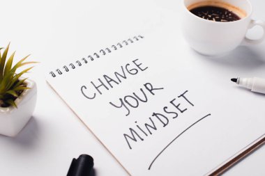 notebook with change young mindset inscription, felt-tip pen, coffee cup and potted plant on white surface clipart