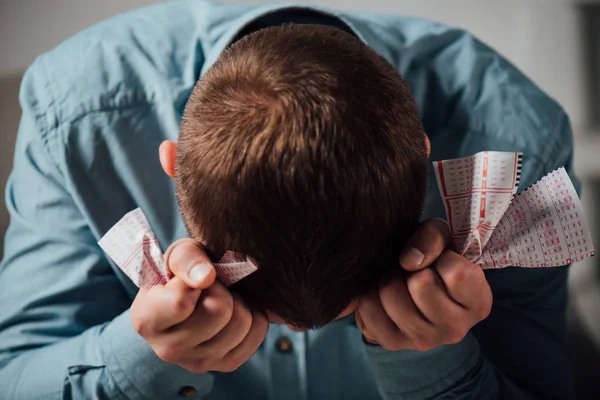 Unhappy Man Sitting Bowed Head While Holding Crumpled Lottery Tickets — Stock Photo, Image