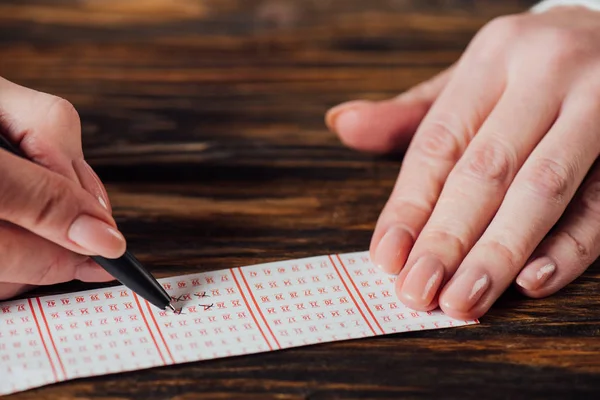 用木制桌子上的笔划彩票中赌徒标记数字的剪影 — 图库照片