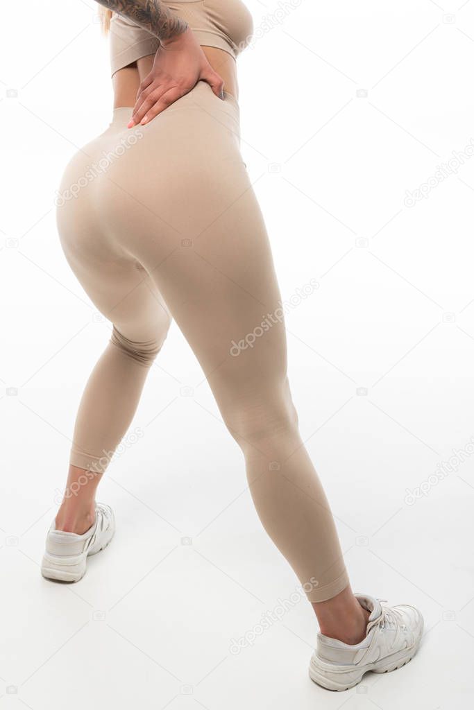 cropped view of tattooed twerk dancer in beige leggings posing isolated on white