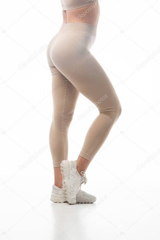 cropped view of twerk dancer in beige leggings posing in smoke isolated on white