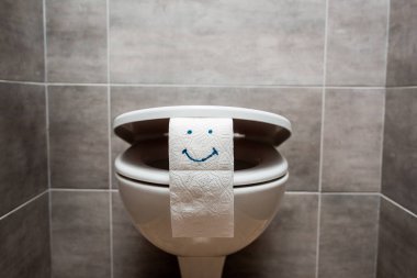 Modern tuvaletlerde seramik temiz klozet ve gülen yüzlü tuvalet kağıdı. 