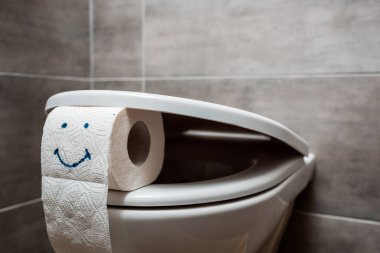 Modern tuvaletlerde seramik temiz klozet ve tuvalet kağıdına gülümseyen yüzle yakın görüş.