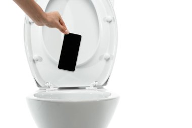 Beyazlara izole edilmiş seramik temiz klozet içinde boş ekranlı akıllı telefonu atan kadın görüntüsü.