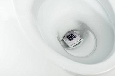 Kyiv, Ukrayna - 7 Kasım 2019: beyaz üzerine izole edilmiş seramik temiz klozet içerisinde süper uygulamalı akıllı telefonun yakın görüntüsü
