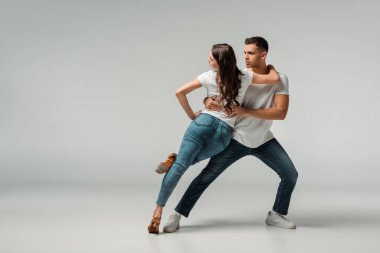 dancers in t-shirts and jeans dancing bachata on grey background  clipart