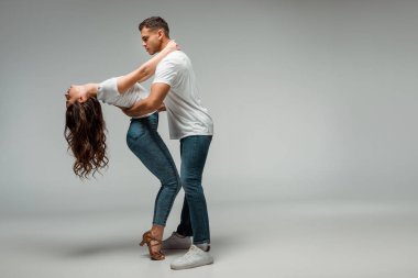 Gri arka planda dans eden dansçıların tişörtleri ve kot pantolonları. 