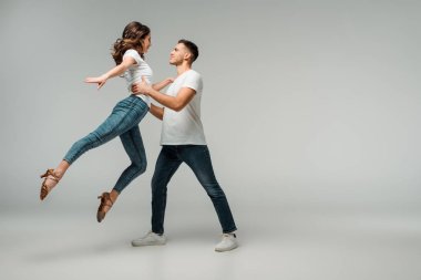 Gülümseyen dansçıların tişörtleri ve gri arka planda dans eden kot pantolonları. 