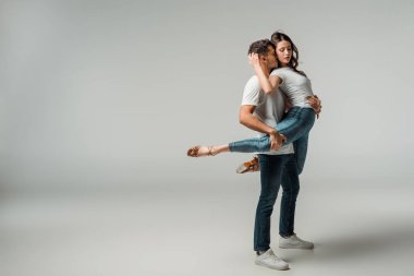 Gri arkaplanda dans eden tişörtlü ve kot pantolonlu dansçılar 