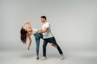 Gri arka planda kot pantolonlu dansçılar dans ediyor. 
