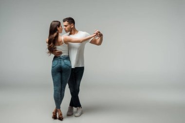 Gri arka planda kot pantolonlu dansçılar dans ediyor. 
