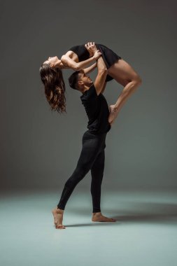 Yakışıklı ve çekici dansçıların yan görünüşü karanlık arka planda çağdaş dans ediyor. 