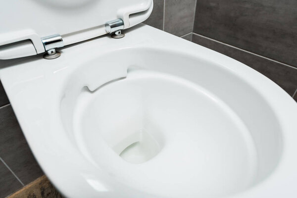 close up view of clean ceramic clean toilet bowl in modern restroom with grey tile