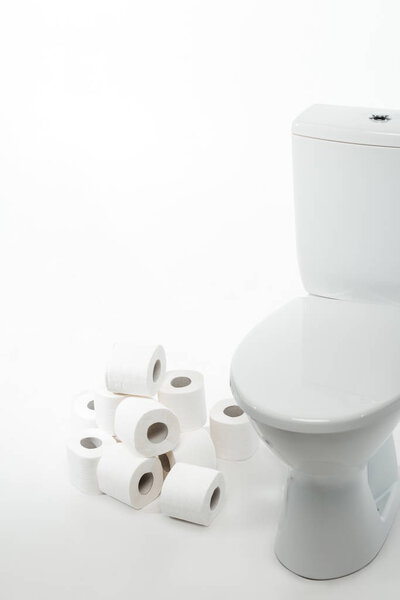 ceramic clean toilet bowl with rolls of toilet paper on white background
