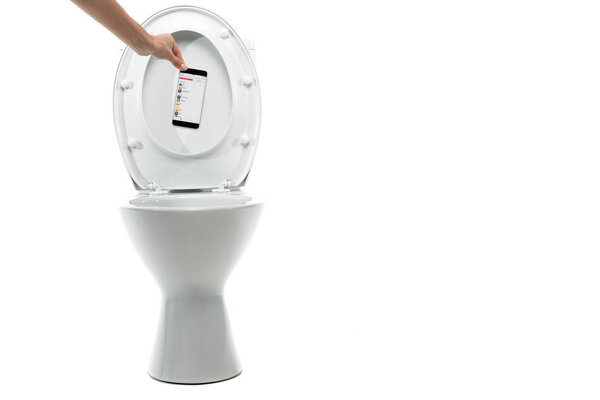 KYIV, UKRAINE - NOVEMBER 7, 2019: cropped view of woman throwing away smartphone with apple music app in ceramic clean toilet bowl isolated on white