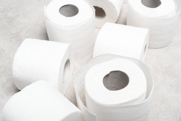 close up view of rolls of toilet paper on grey textured surface