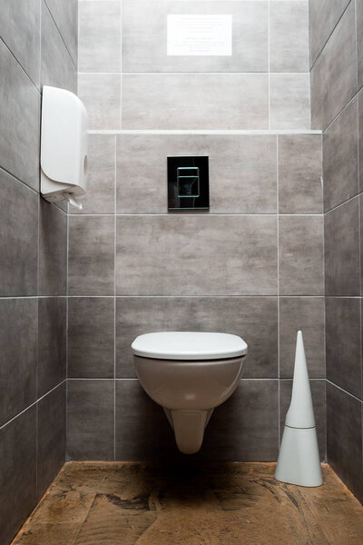 interior of grey modern restroom with toilet bowl near toilet brush