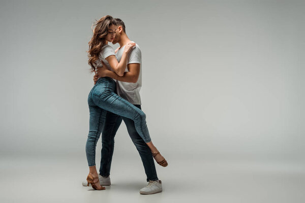 танцоры в футболках и джинсах, танцующие бачату на сером фоне
 