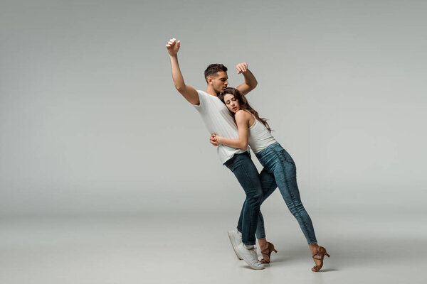 танцоры в джинсах в джинсах танцуют бачату на сером фоне
 