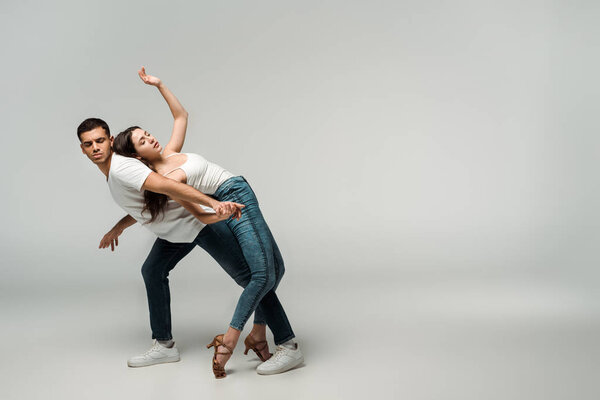 dancers with closed eyes dancing bachata on grey background 