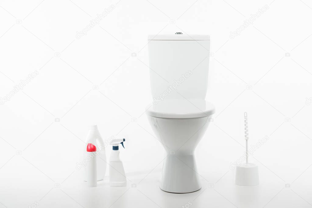 ceramic clean toilet bowl near toilet brush and cleaning supplies isolated on white