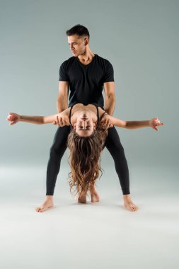 Yakışıklı ve çekici dansçılar gri arka planda çağdaş dans ediyorlar. 