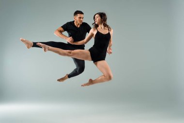 Yakışıklı ve çekici dansçılar gri arka planda çağdaş dans ediyorlar. 