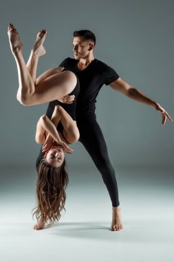 Yakışıklı ve çekici dansçılar karanlık arka planda çağdaş dans ediyorlar. 