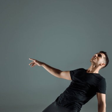 Gri üzerinde çağdaş dans eden siyah tişörtlü yakışıklı dansçı. 