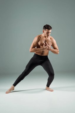 Siyah taytlı yakışıklı dansçı karanlık arka planda çağdaş dans ediyor.