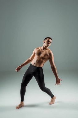 Siyah taytlı yakışıklı dansçı karanlık arka planda çağdaş dans ediyor.