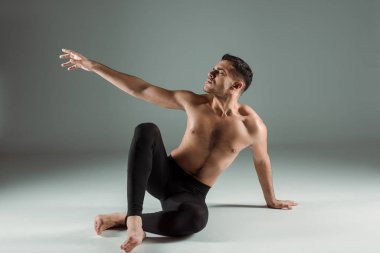 Siyah taytlı yakışıklı dansçı. Gözleri kapalı. Karanlık arka planda dans ediyor.