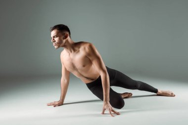 Siyah taytlı yakışıklı dansçı karanlık arka planda çağdaş dans ediyor.