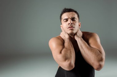 Gri arka planda çağdaş dans eden kapalı gözlü yakışıklı dansçı.