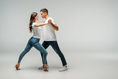 Gri arka planda dans eden dansçıların tişörtleri ve kot pantolonları. 