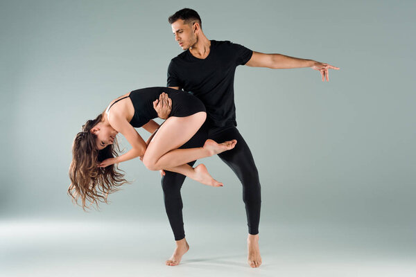 красивые и привлекательные танцоры, танцующие современно на сером фоне
 