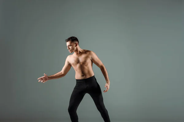 ブラック レギンスのハンサムなダンサーが現代的にグレーで孤立して踊る — ストック写真