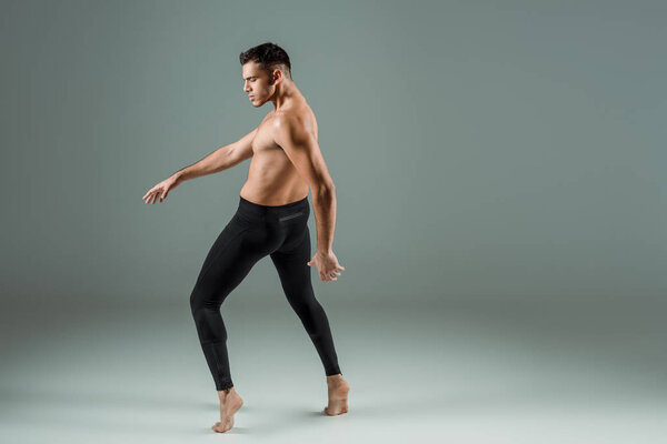 side view of handsome dancer in black leggings dancing contemporary on dark background