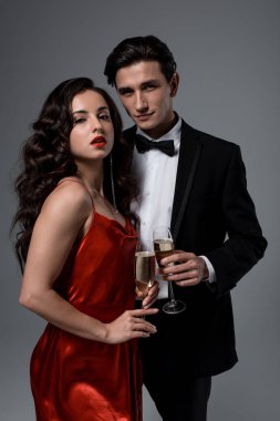 Romantik şenlik çifti ellerinde şampanya kadehleriyle, gri yolda izole halde.