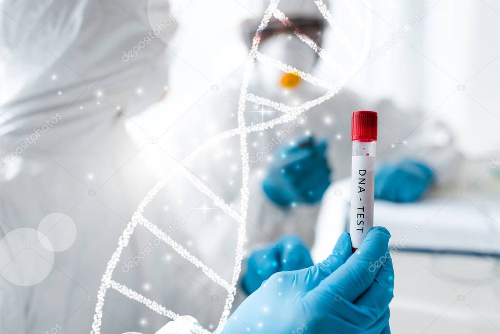 selective focus of scientist and her african american colleague doing dna test near dna illustration 