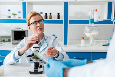 selective focus of biologist talking with african american colleague in lab  clipart