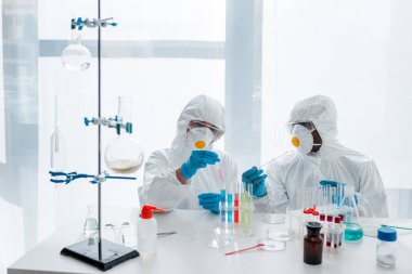 Koruyucu giysiler içindeki çok kültürlü bilim adamları laboratuvarda DNA testi yapıyorlar. 