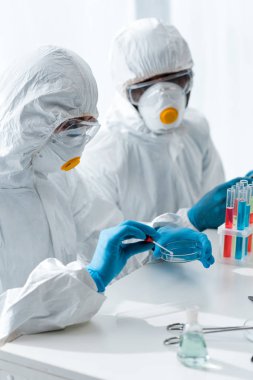 Koruyucu giysiler içindeki çok kültürlü bilim adamları laboratuvarda DNA testi yapıyorlar. 