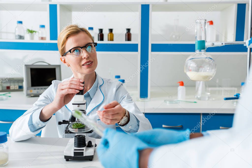 selective focus of biologist talking with african american colleague in lab 