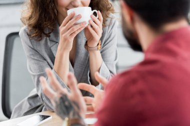 Hesap yöneticisinin elinde bardak tutarken ve iş arkadaşını dinlerken çekilmiş görüntüsü 