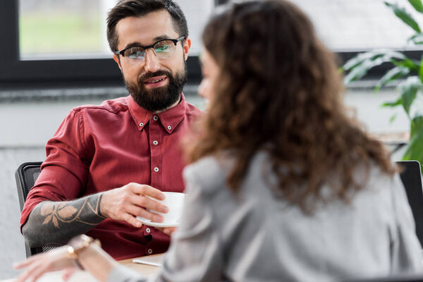 selective focus of smiling account manager holding cup of coffee 