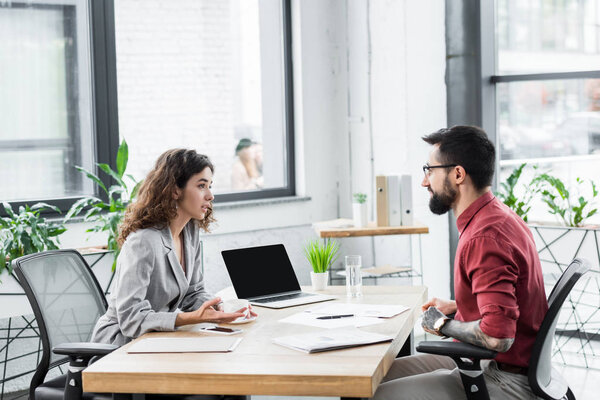 side view of account managers talking and sitting at table 