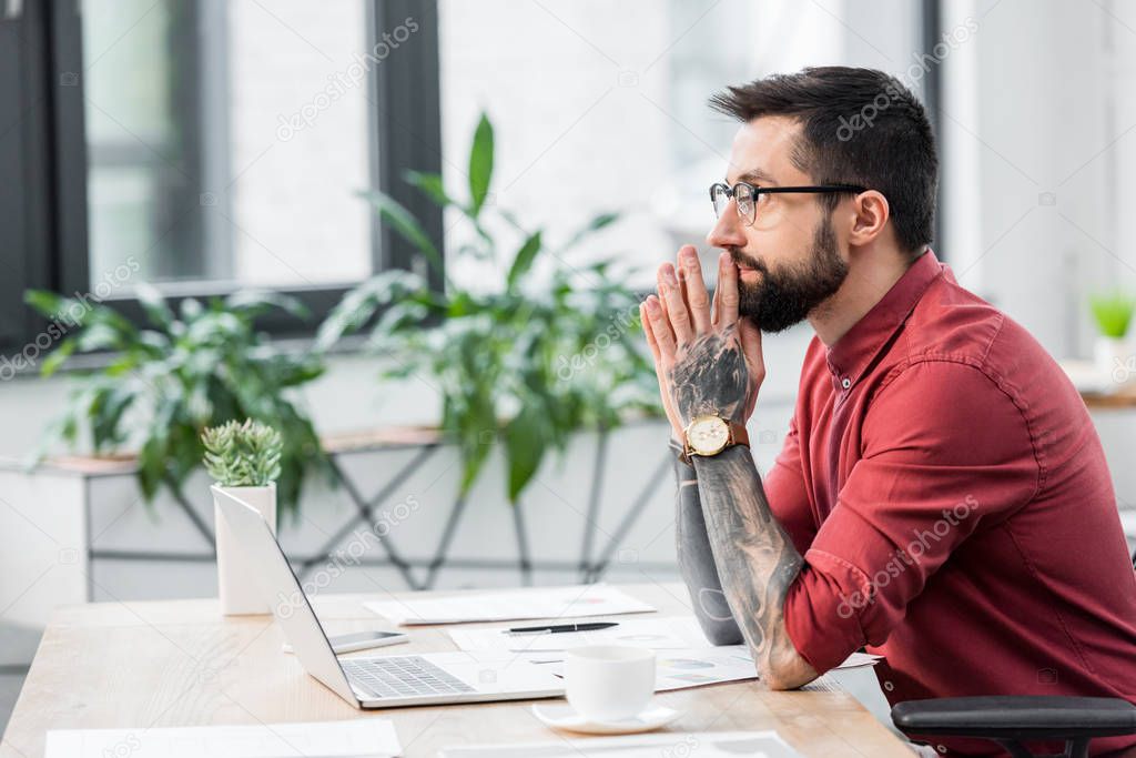 side view of pensive account manager sitting at table 